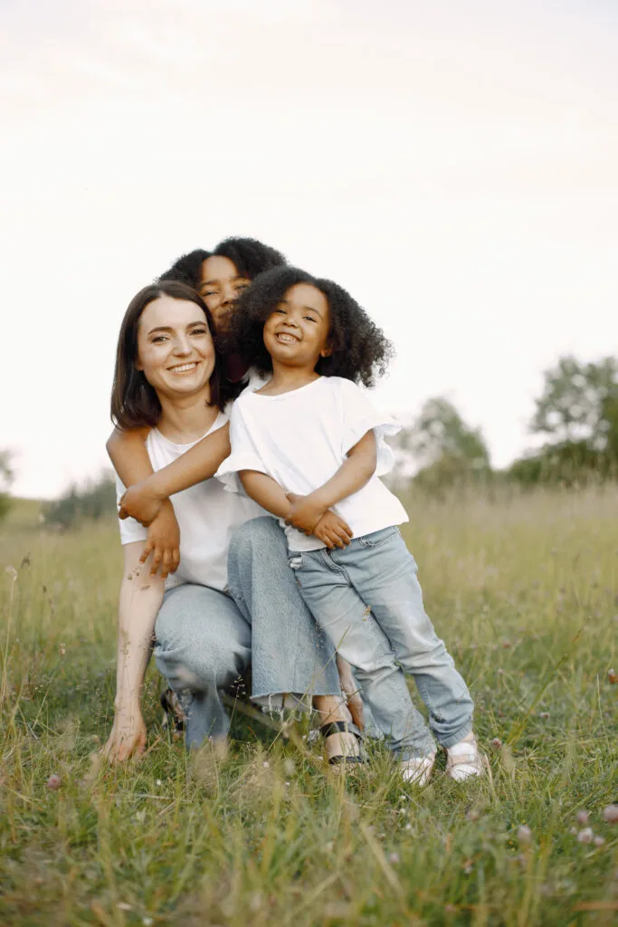caucasian mother embracing her mixed race daughters